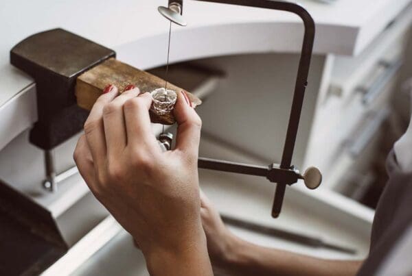 Jewelers Insurance - Close-up of a Young Female Jeweler’s Hands Working on a New Silver Ring at Her Workbench