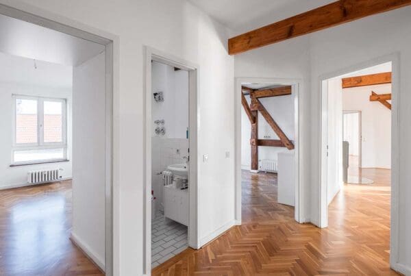 Vacant Home Insurance - Hardwood Floors and Exposed Wooden Beams of a Vacant Penthouse Apartment after a Renovation with Multiple Rooms and View of Bathroom